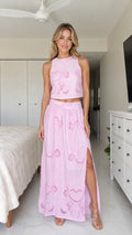 Front view of model wearing pink two-piece crop top and maxi skirt set