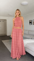 Model wearing pink halter ruched crop top and maxi skirt two-piece set front view
