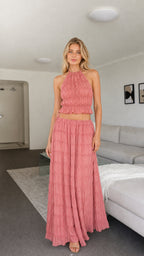 Model wearing pink halter ruched crop top and maxi skirt two-piece set front view
