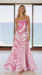 Front view of woman wearing pink swirl print strapless top and matching maxi skirt