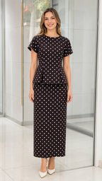 Front view of black polka dot peplum top and midi skirt set on model