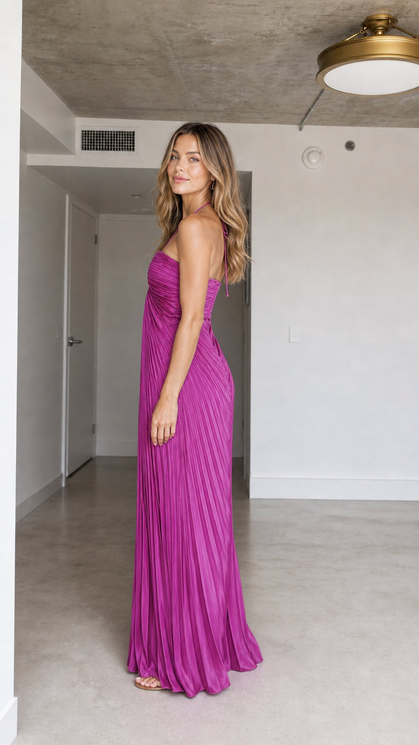 Side profile of model wearing Fuchsia pleated maxi dress