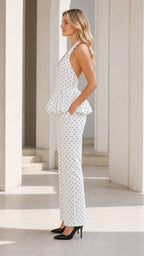 Side profile of model wearing white polka dot halter jumpsuit