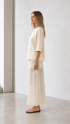 Side profile view of woman in cream two-piece outfit
