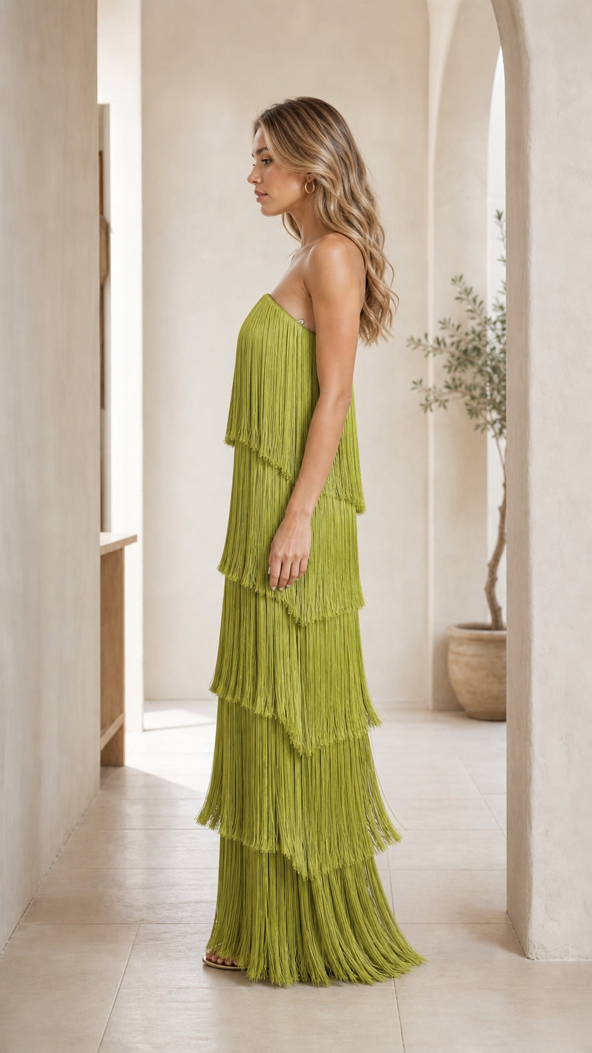 Side profile view of woman in olive green fringe maxi dress