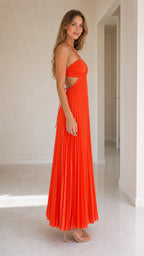 Side profile of model in orange pleated maxi dress with cut-outs