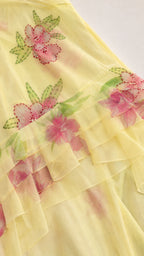 Close-up detail of floral embroidery and tiered ruffles on yellow dress