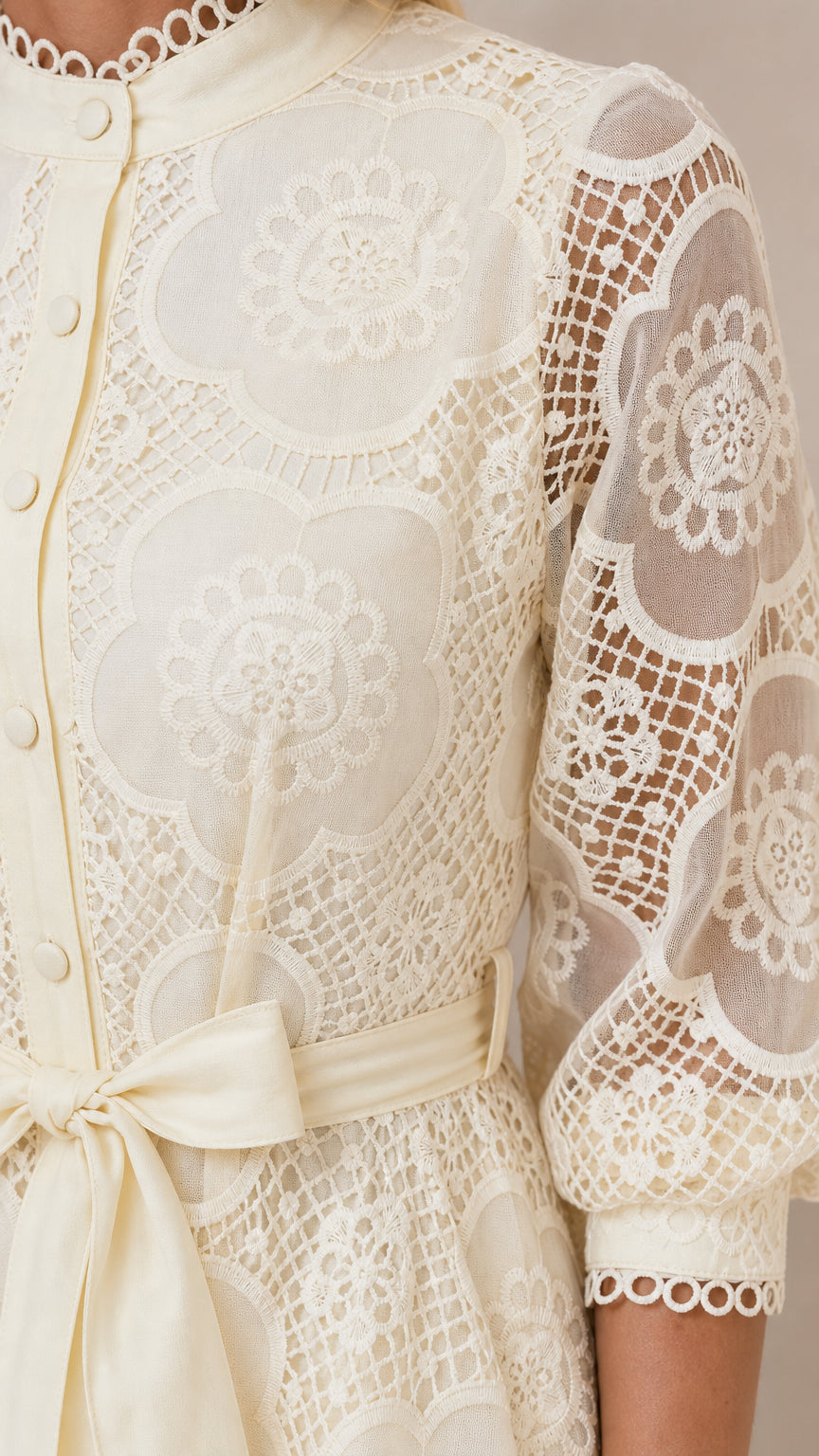 Close-up detail of lace pattern and button closure on ivory dress