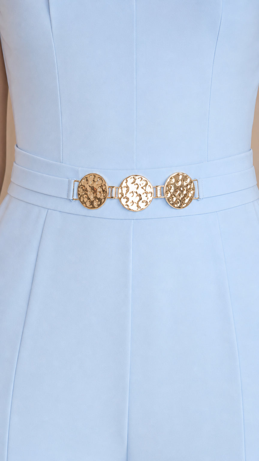 Close-up of metallic gold hardware belt detail on light blue jumpsuit