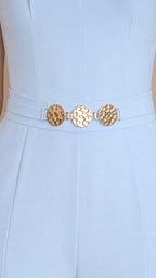 Close-up of metallic gold hardware belt detail on light blue jumpsuit