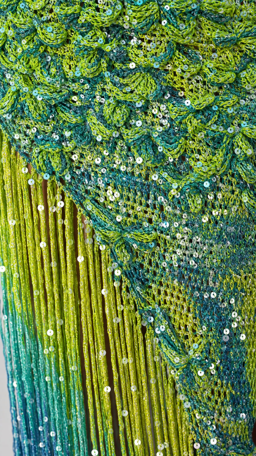 Close-up detail of green blue sequin texture and ombre fringe hem