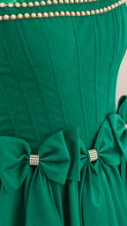 Close-up of pearl trim and rhinestone bows on green dress