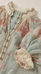 Close-up detail of scalloped collar and fabric texture of floral blouse