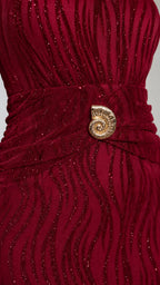 Close-up of gold shell belt and wavy texture on burgundy dress