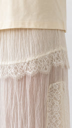 Close-up detail of lace trim and crinkled texture on cream skirt