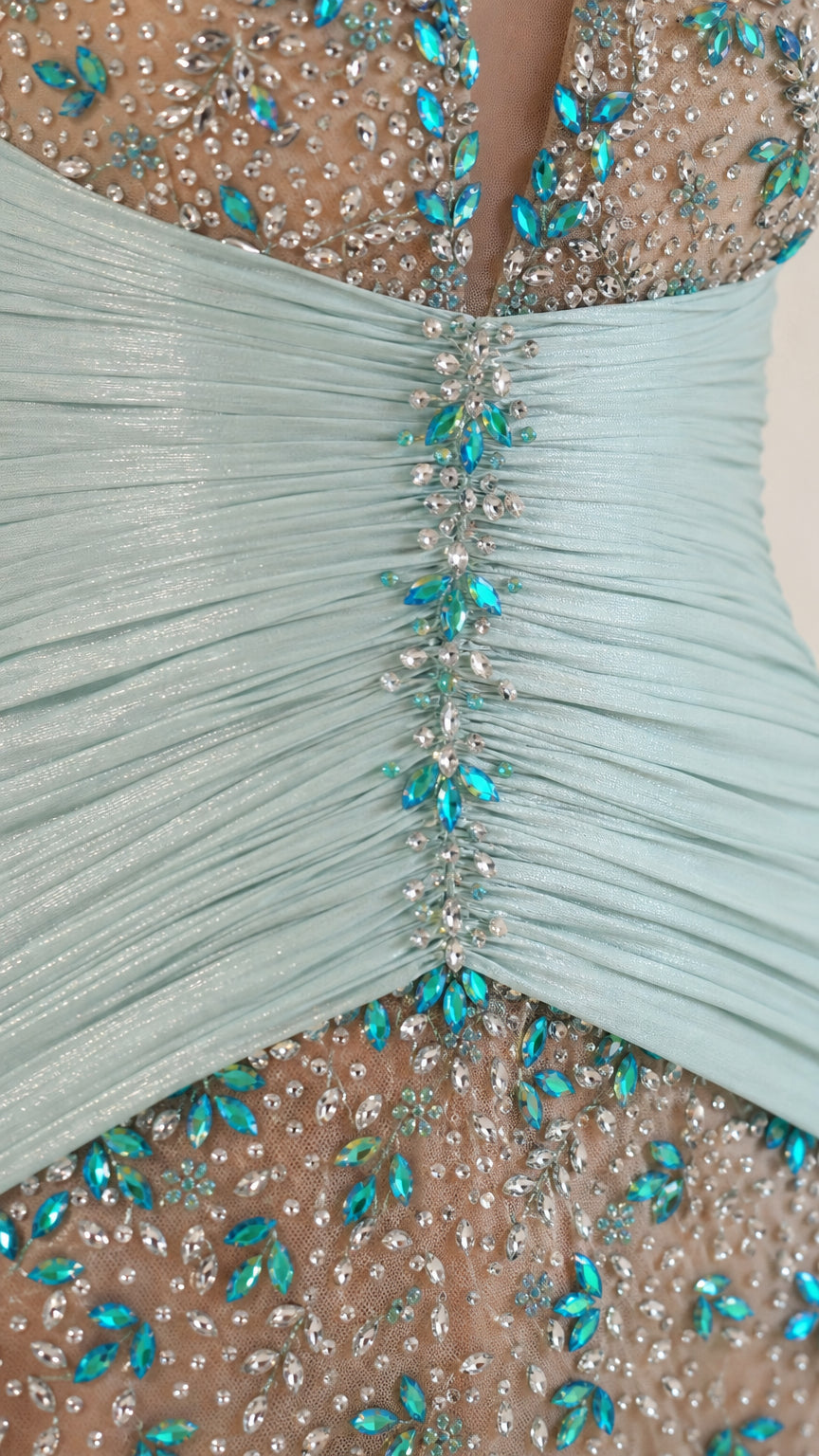 Close-up of crystal embellishments and gathered waist on mint gown