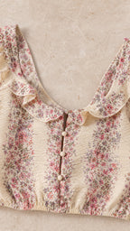 Close-up detail of beige floral crop top with ruffles and buttons