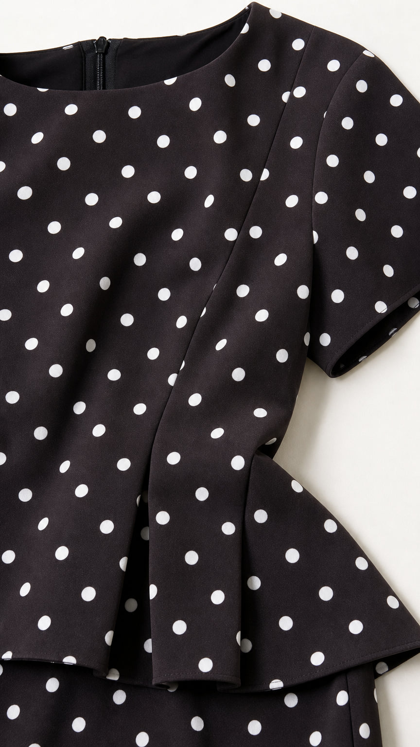 Close up detail of black polka dot fabric and peplum hem