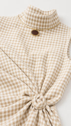 Close-up detail of mock neckline and waist knot on beige gingham dress