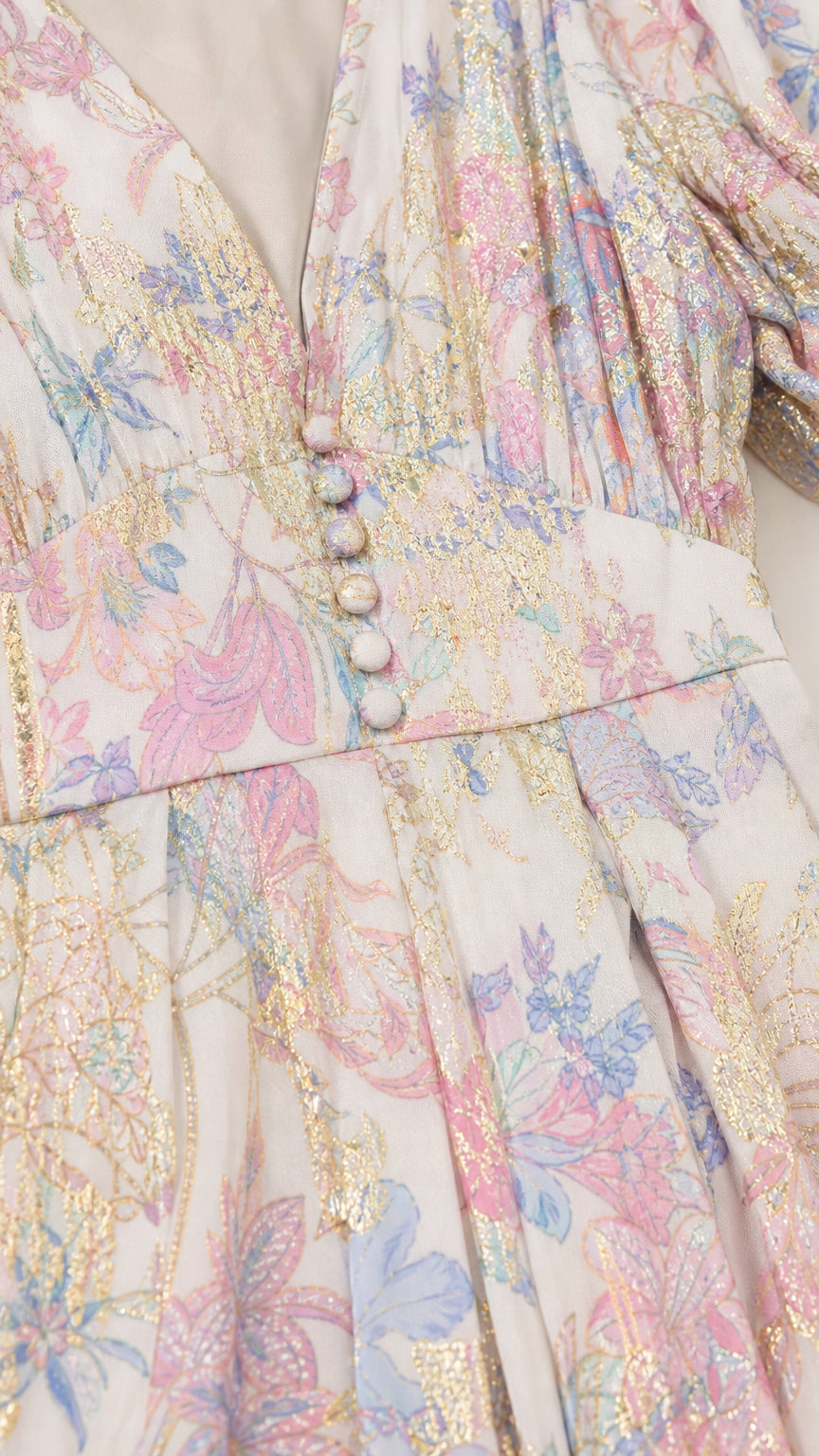 Close-up detail of V-neckline, covered buttons, and metallic floral fabric