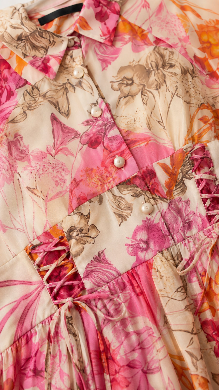 Close-up detail of shirt collar, pearl buttons, and lace-up waist on floral dress