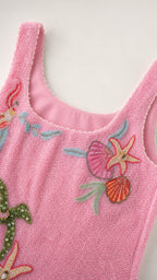 Close-up detail of scoop neckline and beadwork on pink dress